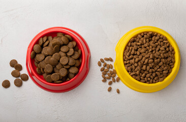 Dry food for cats and dogs in a yellow and red bowl on a gray cement background.Vitamins and nutrients for good health and pet energy.
