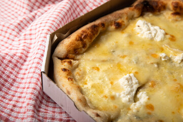 Delicious Italian cheese pizza on a kitchen towel. Pizza in a box. Pizza delivery. Composition on black texture background. View from above. Copy space. Italian food. 