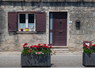 Naklejka premium Beautiful window with flowers in an old medieval house in southern Italy. Home comfort and harmony.