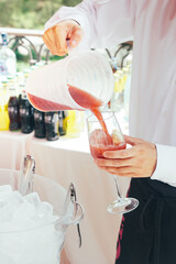 waiter pouring a cocktail into a glass and a bucket full of ice