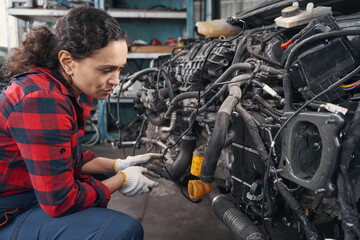 Fototapeta na wymiar Young working woman checking condition of car motor