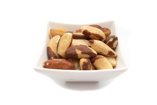 A white bowl with brazil nut or amazon nut, isolated on white background. Bertholletia excelsa is a tree of the Lecythidaceae family, native to South America, endemic to the Amazon.