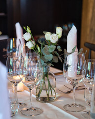 Decoration arrangement of glasses, flowers, napkins, and small burning candles for a wedding party. 