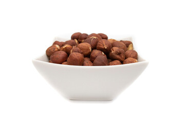 A white bowl with hazelnuts, isolated on white background.Hazelnut is the nut-like fruit of the common hazel, Corylus avellana. Etymologically it comes from the Latin nux abellana.