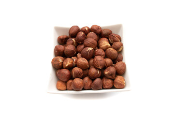 A white bowl with hazelnuts, isolated on white background.Hazelnut is the nut-like fruit of the common hazel, Corylus avellana. Etymologically it comes from the Latin nux abellana.