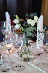 Table arranged for a formal dinner with candles and flowers on a white table cloth. 