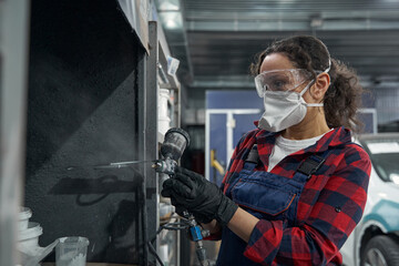 Fototapeta na wymiar Attentive female mechanic using spray compressor for work