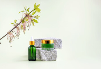 bottles for cosmetics on the podium made of stone and branches of flowering ash maple on a light...