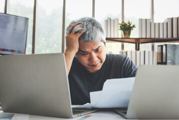 Fototapeta premium Asian business men Feeling stressed While he looks at unsuccessful earning from a paper report, at workplace, to people and business concept.