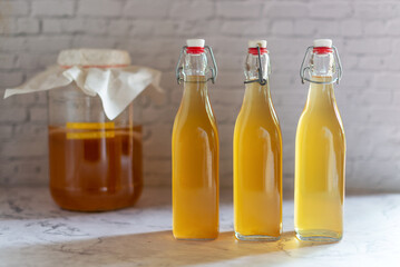 Kombucha in glass bottle on white table, fermented tea drink, healthy beverage.