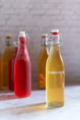 Kombucha in glass bottle on white table, fermented tea drink, healthy beverage.