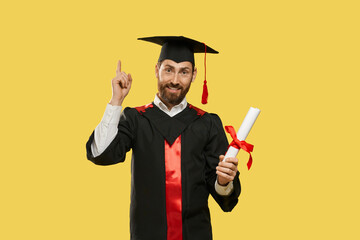 Front view of happy young man graduating from university, college. Boy with beard standing,...