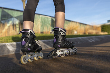 A woman tightens roller skates on the path, rollerblading. Woman's legs with roller blades at sunny...
