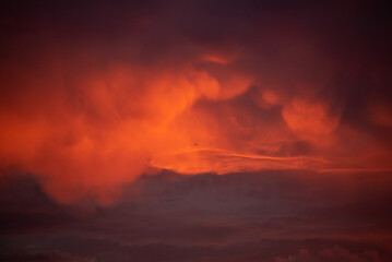 An airplane flies through a cloudy sunset
