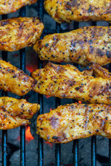 Tasty pieces of chicken breast on the grill with flames