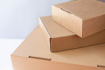 Three cardboard packing boxes stand stacked on top of each other on a gray background.