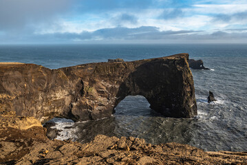 Fototapeta na wymiar Scenic view of the iconic rock arch of Dyrhólaey peninsula, seen from a lookout near the Dyrhólaeyjarviti lighthouse, Southern region, Iceland