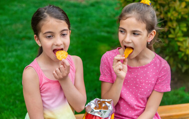 Children eat chips in a friend's park. Selective focus.