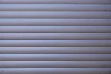 Grau-wei&szlig;e gestreifte Jalousie vor Fenster 