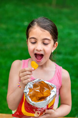 The child eats chips in the park. Selective focus.