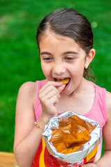 The child eats chips in the park. Selective focus.