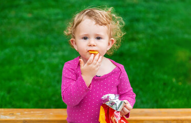 The child eats chips in the park. Selective focus.