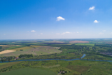 The countryside on a bright sunny day, fields and villages. Steppe plain area with a river. Bird's eye view. View from a drone.