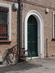 Fototapeta na wymiar House facade, elegant green door. Bicycle leaning against the wall.