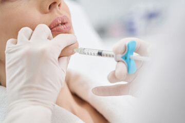 Doctor cosmetologist making beauty injection into woman chin
