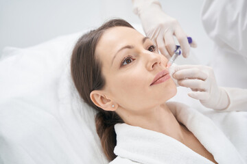 Woman receiving contour plastic injection in beauty clinic