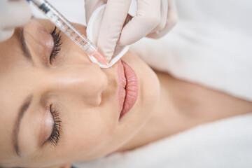 Cosmetologist doing beauty injection in woman lips