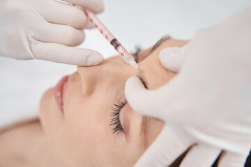 Woman receiving face lifting injections treatment in beauty clinic