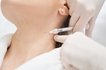 Obraz na płótnie Canvas Doctor beautician doing injection into woman neck in beauty salon