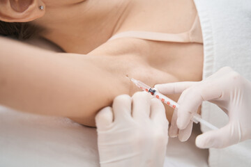 Woman receiving underarm injection in beauty salon - obrazy, fototapety, plakaty