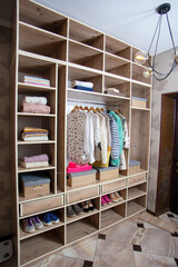 Big wardrobe with different clothes and accessories in dressing room