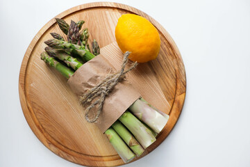 a bunch of asparagus, lemon, eggs and spices on a wooden table