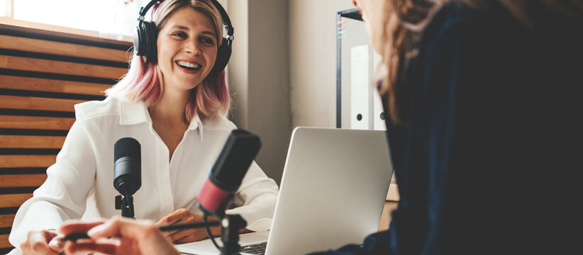Two handsome woman hosts streaming podcast at loft broadcast studio, happy emotions