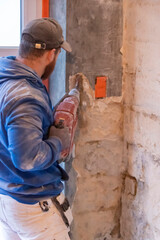 Ouvrier sur chantier enlevant le plâtre d'un mur avec un marteau-piqueur