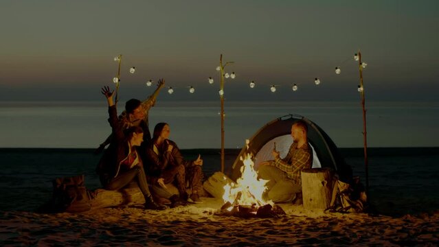 Group of young people having camp on the beach at night