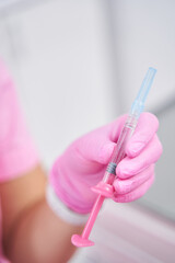 Female medical worker holds hypodermic syringe in her left hand