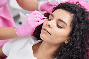Doctor makes schematic dots with white pencil on female face