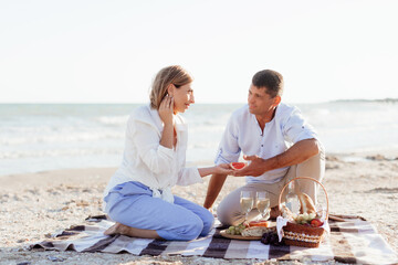 Happy romantic middle aged couple on the beach. Picnic by the sea.
