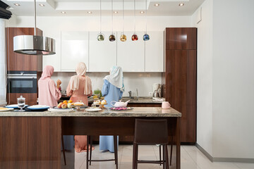 Three Muslim women cooking dinner in kitchen