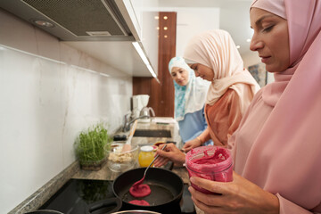 Muslim women cooking together in kitchen at home
