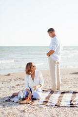 Happy romantic middle aged couple on the beach. Picnic by the sea.