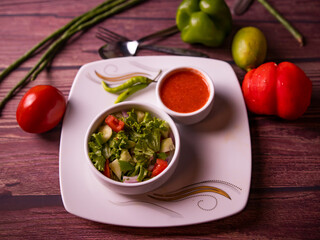 Fresh green salad with tomato, cucumber, salad leaf, and sauce in a bowl top view of healthy food
