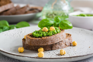 Fresh sandwich with pesto and chickpeas on rye bread on a plate on the table. Close-up