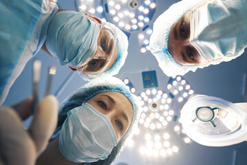 Three surgeons leaning over patient on operating table