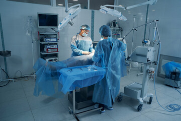 Two surgery experts conducting laparoscopic operation on patient