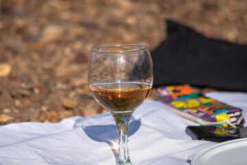 A glass of wine on a white tablecloth in nature.